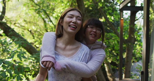 Portrait of asian mother and daughter embracing in garden and smiling. at home in isolation during quarantine lockdown.
