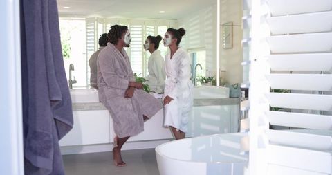 Couple enjoying skincare and relaxation in sunlit modern bathroom
