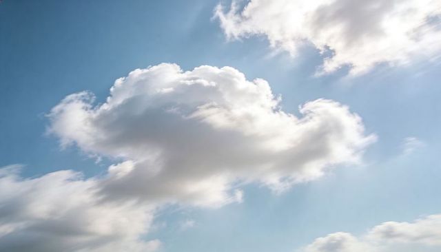 Drifting Sunlit Cumulus Cloud Over Wide Blue Sky With Soft Wisps and Rays