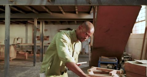 Skilled Carpenter Measuring Wood Frame in Workshop