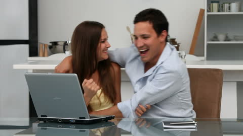 Happy Couple Using Laptop in Kitchen