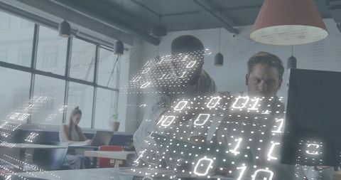 Software developers collaborating over monitor with binary overlay in modern office
