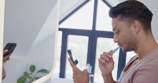 Young man multitasking brushing teeth and checking smartphone - Download Free Stock Images Pikwizard.com