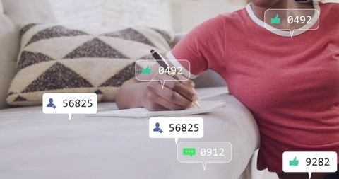 Woman writing on sofa with social media engagement overlays for content planning