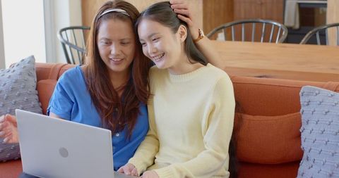 Mother and Daughter Enjoy Moments with Laptop at Home