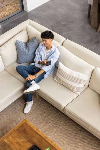 Smiling Man Relaxing on Sofa with Smartphone in Modern Living Room