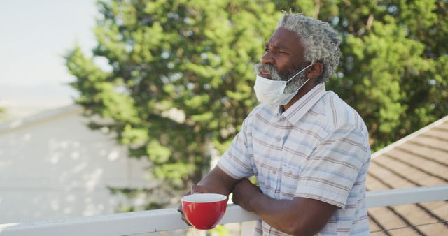 Man Enjoying Fresh Air While Wearing Face Mask and Holding Coffee Cup on Balcony - Download Free Stock Images Pikwizard.com