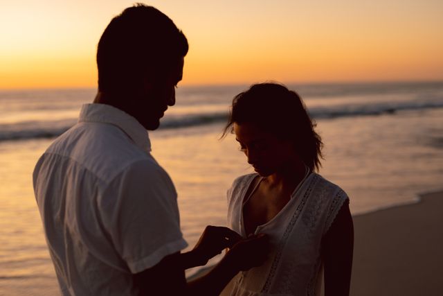 Couple sharing intimate moment on beach during sunset. Ideal for use in romantic, travel, lifestyle, and relationship-related projects. Perfect for advertisements, blog posts, and social media content focusing on love, travel, and serene outdoor experiences.