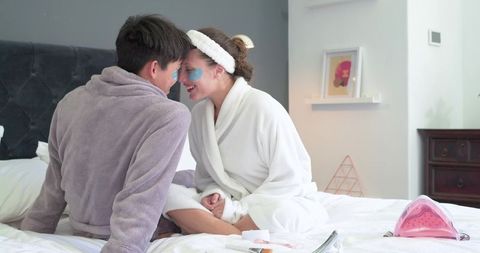Couple enjoying cozy at-home spa morning applying eye patches wearing plush robes