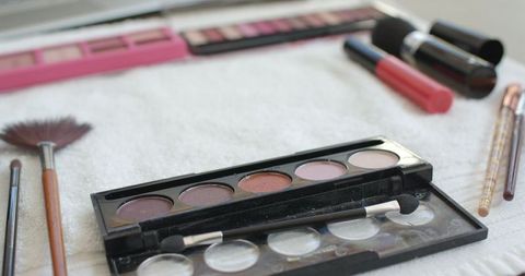 Neutral eyeshadow palette with makeup brushes on white background