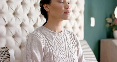 Woman Meditating Peacefully in Cozy Bedroom Environment
