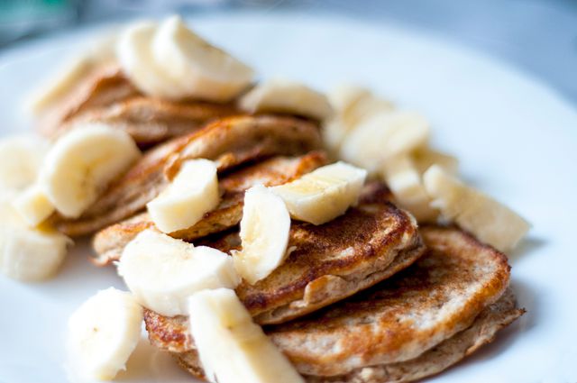 Pancakes topped with fresh banana slices provide a nutritious breakfast. Useful for articles or blogs focusing on healthy recipes, breakfast ideas, or food and nutrition. Suitable for social media posts, cooking websites, food magazines, and health promotion materials.