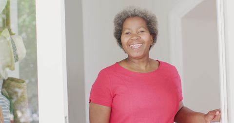 Senior african american woman joyfully greeting visitor at door