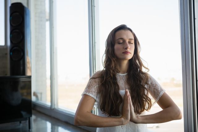 Young woman with eyes closed doing yoga at office