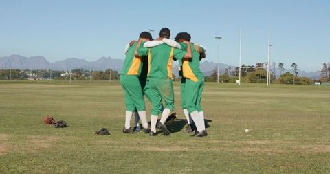 Cricketers Huddling on Grass Field Wearing Green Kits Embracing Team Spirit and Unity