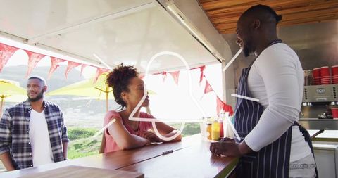 Street food truck vendor interacting with customers at scenic outdoor cafe