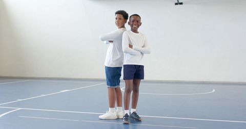 Confident boys standing back-to-back on gym court