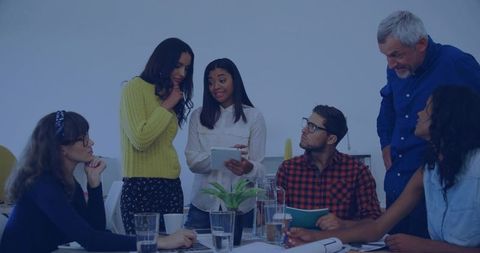 Presenter showing tablet to diverse team during collaborative office meeting and discussion