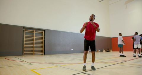 Athlete adjusting shirt during team warmup on indoor basketball court with hardwood flooring