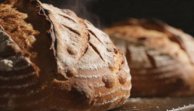 Steaming artisan sourdough loaf with crusty scoring and rustic flour dusting
