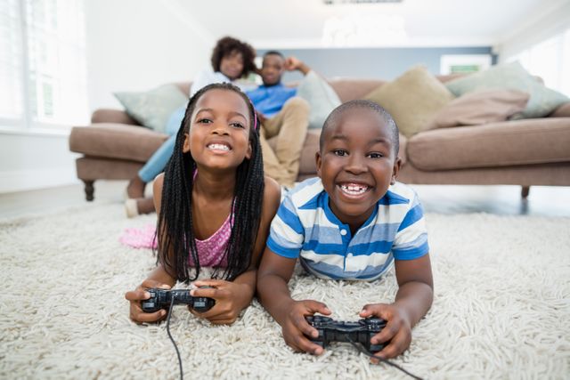 Siblings lying on rug and playing video game at home