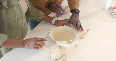 African American couple shaping pie crust together in bright home kitchen baking moment