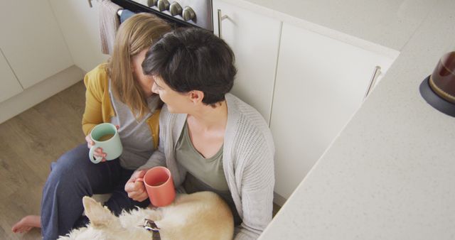 Caucasian lesbian couple embracing each other while having coffee together in the kitchen at home. lgbt relationship and lifestyle concept