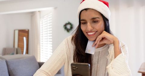 Cheerful Indian Woman with Santa Hat Shopping Online with Smartphone