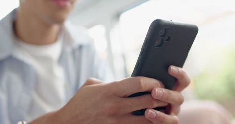 Man Holding Smartphone by Window in Bright Ambient Lighting