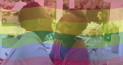 Smiling woman embracing child on backyard patio with rainbow pride overlay for family