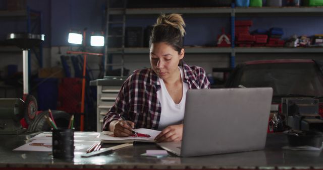 Female mechanic taking notes and using laptop at a car service station. automobile repair service