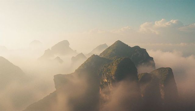 Majestic Peaks Emerging Through Mystical Clouds During Sunrise