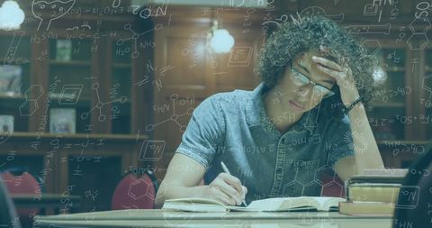 Focused Student Writing Notes in Library with Chemistry Illustrations