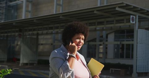 Professional Plus Size Woman on Phone in Urban Setting with Notebooks