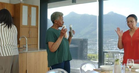 Senior african american women seasoning meal in modern kitchen with mountain view