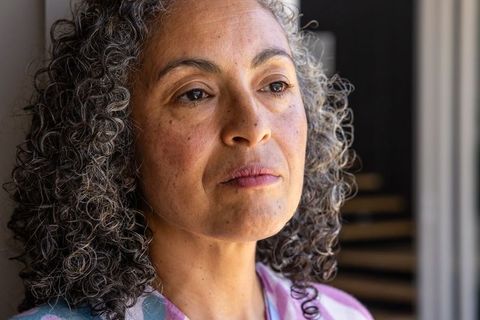 Contemplative senior african american woman gazing out window closeup with curly gray hair