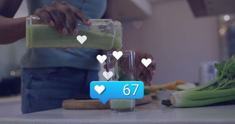 Pouring green smoothie into glass on kitchen counter with social media like notifications