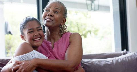 Joyful Embrace Between Grandmother and Granddaughter on Sofa