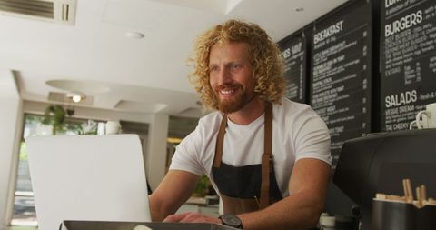 Friendly Barista Using Laptop in Modern Cafe