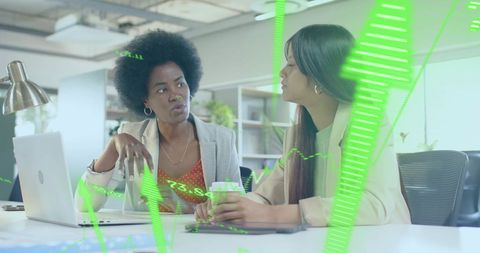 Businesswomen Discussing Financial Strategies Over Data Visualization