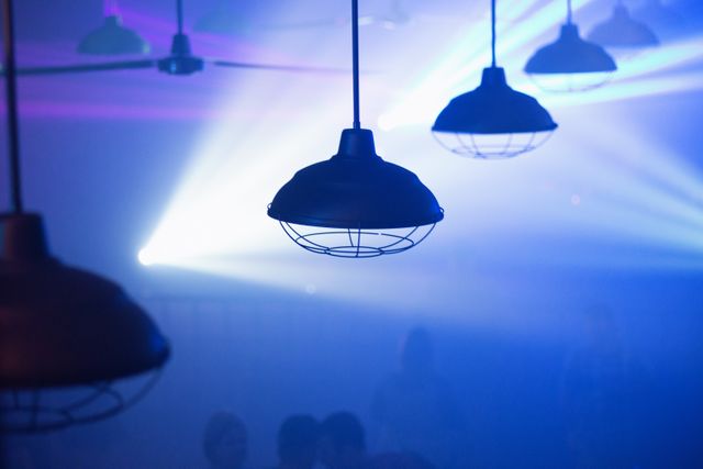 Moody shot showing industrial hanging lights in a nightclub with fog and colorful LED lights. Perfect for use in contexts related to nightclubs, parties, events, club culture, and nightlife promotions.