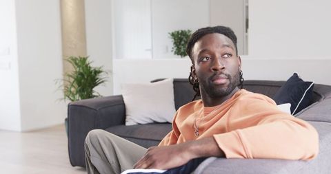 African American man relaxing on modern gray sectional sofa in bright living room