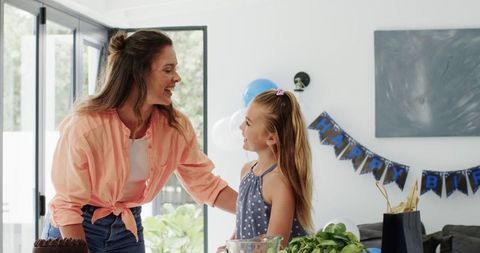 Mother and daughter preparing birthday party in bright living room