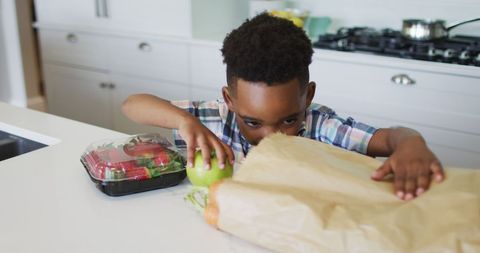African American Boy Unpacking Groceries in Modern Kitchen