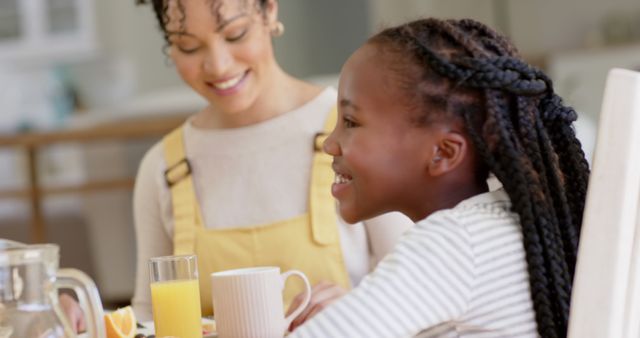Mother bonding with daughter during breakfast. Warm family atmosphere with positive emotions. Use for themes related to family, morning routines, parent-child relationships, and healthy eating.