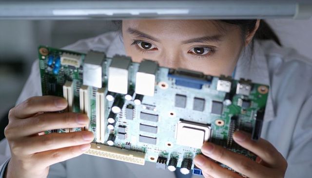 Female technician inspecting computer motherboard closeup showing precision electronics