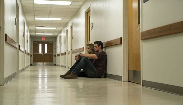 Couple sitting in hospital corridor showing exhaustion and emotional support after injury