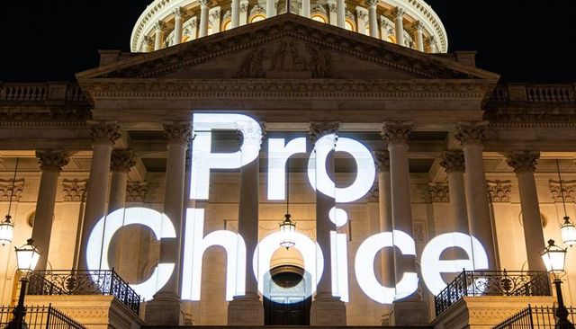 Projecting pro choice slogan on classical capitol facade at night with corinthian columns