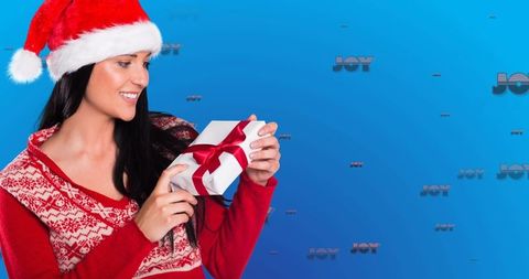 Smiling woman in santa hat holding christmas gift with joyful background