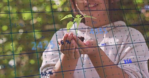 Young girl holding seedling with digital data overlay